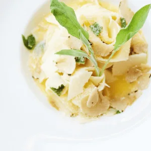 Bord lintpasta met salieblaadjes in een lichte saus, van bovenaf