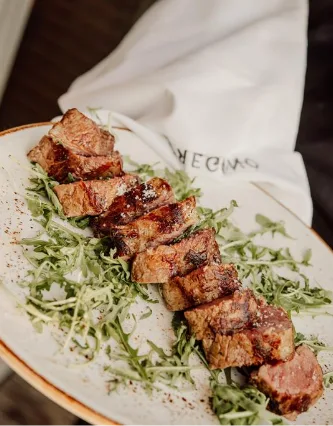 Gesneden gegrilde steak op rucola, met een Oregano-servet op de achtergrond